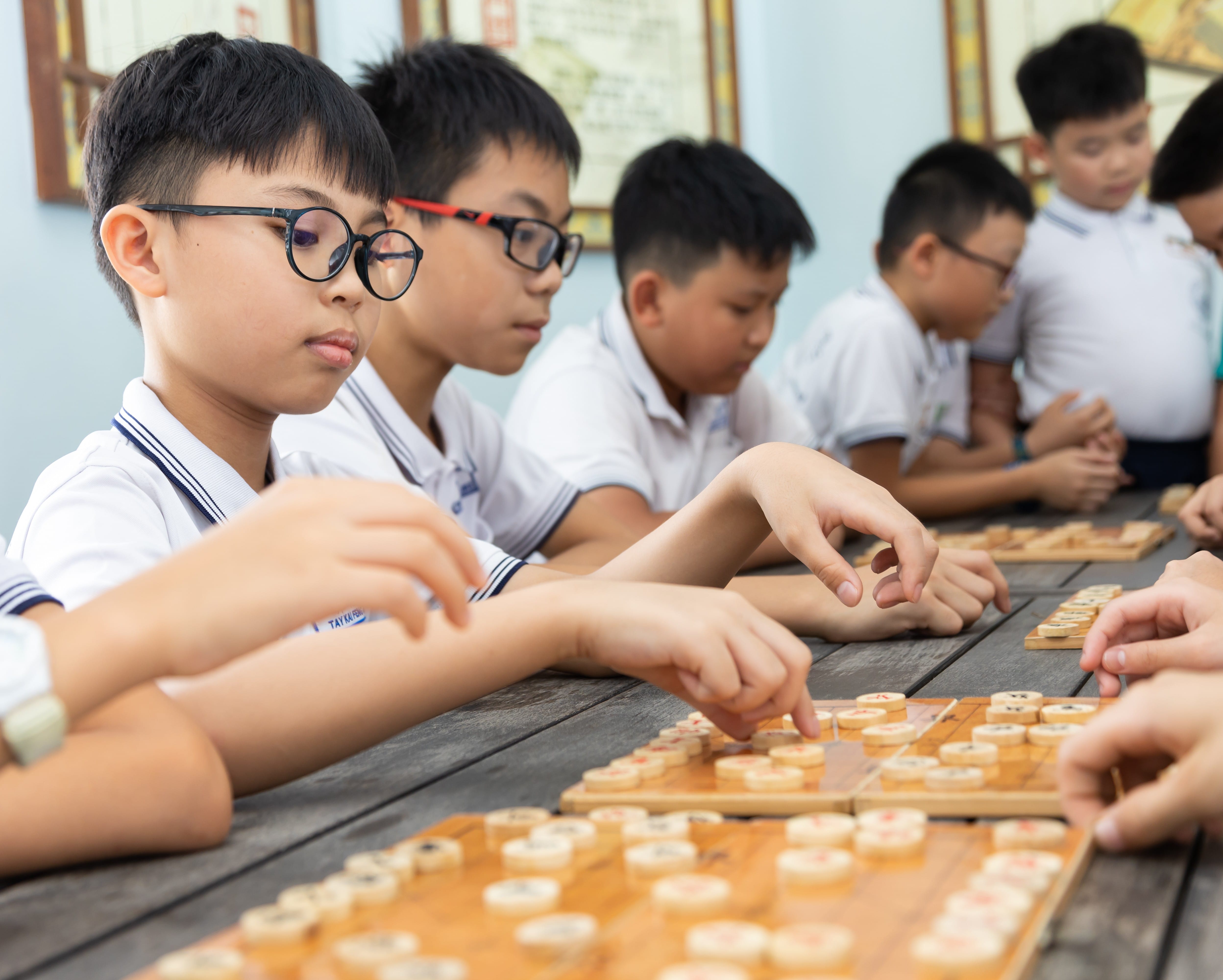 A group of children concentrating as they consider their next moves while playing Chinese chess.